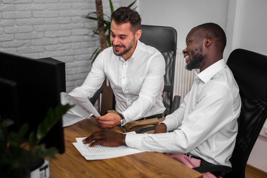 Two colleagues reviewing printed documents together at a desk