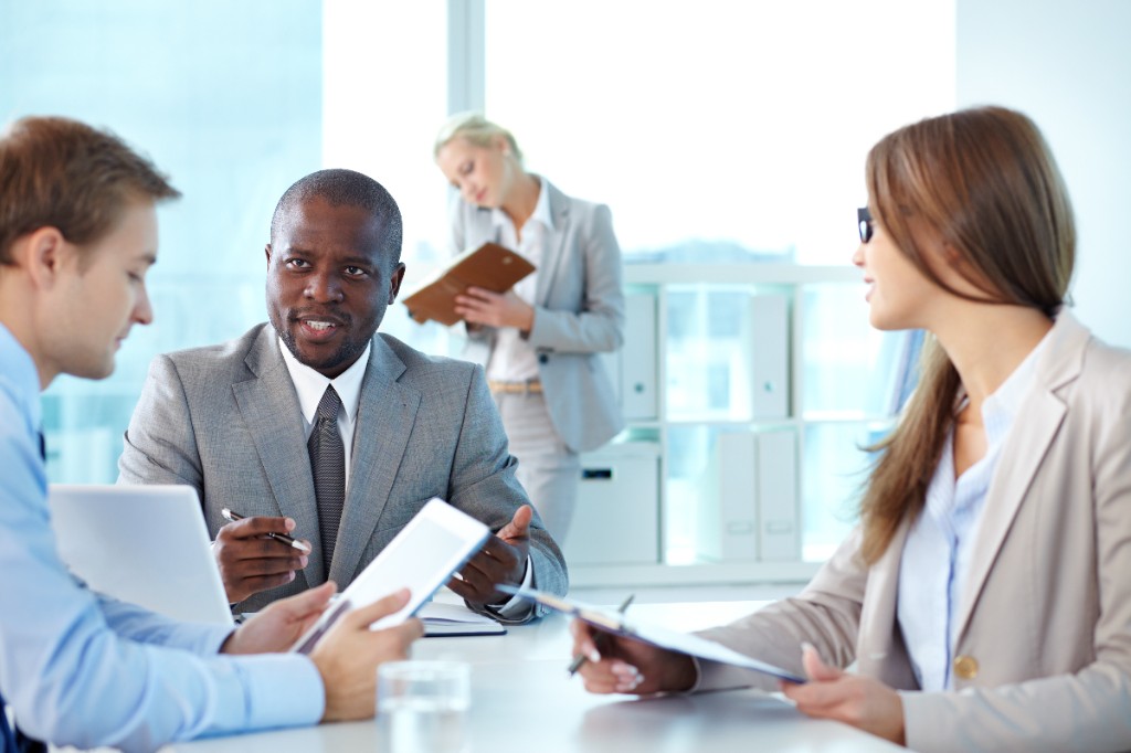 A consultant leading a discussion around a meeting table